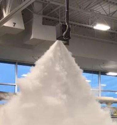 A ceiling-mounted fog head discharging downward into a retail sales floor in a dense white cone.